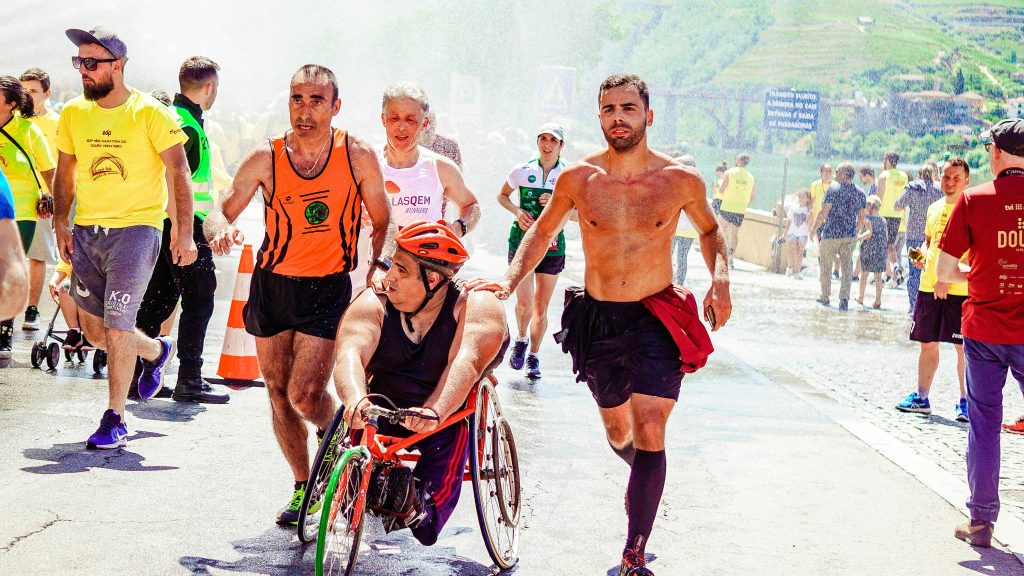 A dynamic scene of athletes, including a wheelchair participant, competing in an outdoor marathon.